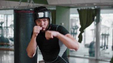 Yumuşak koruyucu kasklı genç boksör kameraya gölge boksu yapıyor.