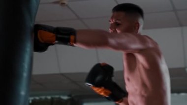 Spor salonunda kum torbasıyla çıplak boksör eğitimi.