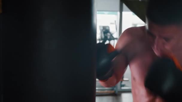 Bez koszuli zły człowiek bokser trening z workiem bokserskim — Wideo stockowe