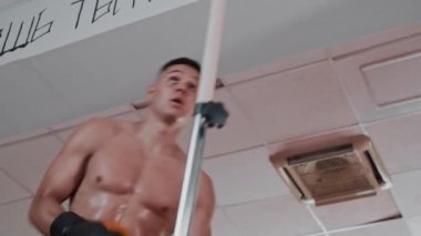 Spor salonunda boks antrenmanı yapan gömleksiz, terli genç adam.