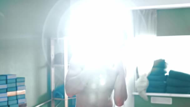 Bezkoszulowy młody człowiek boksuje przed kamerą z jasnym oświetleniem za sobą — Wideo stockowe