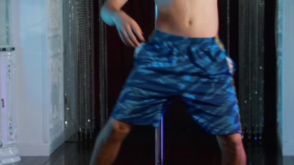 Un giovane uomo a torso nudo che balla su un palo in bicchieri con strass — Video Stock