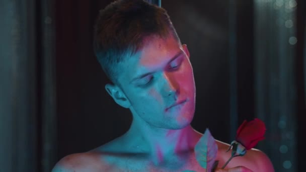 Shirless romantische man ruiken een roos in neon verlichting — Stockvideo