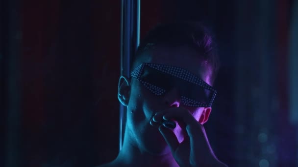 Pretentieuze aantrekkelijke man in de kleuren met strass dampen in de donkere club — Stockvideo