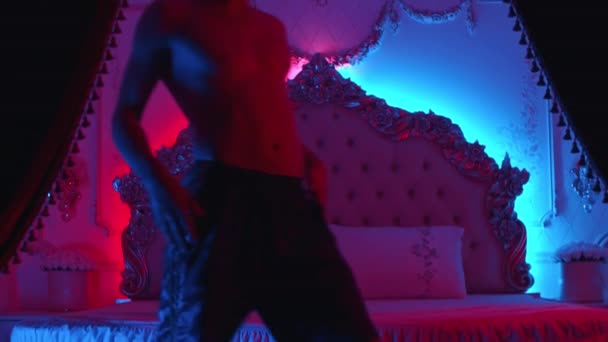 Mladý muž striptér vejde do ložnice a začne svůj excentrický tanec na podlaze — Stock video