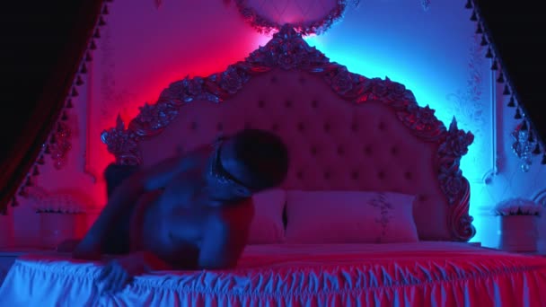 Joven stripper actuando divertido y sexy en la cama - iluminación de neón — Vídeo de stock