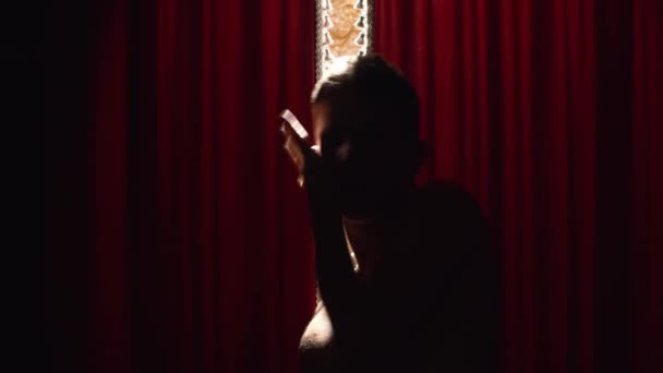Junger Mann führt bizarren Tanz auf rotem Vorhang auf — Stockvideo
