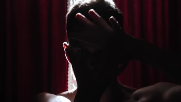 Молодой человек, танцующий странные танцы на фоне красных занавесок в контрастном освещении - глядя в камеру — стоковое видео