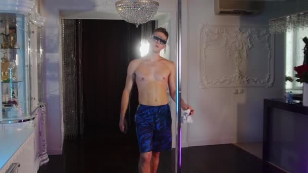 Ung skjorta man strippa i nyanser täckt med strass promenader till stången och börjar torka stången med en trasa — Stockvideo