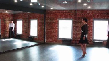 Çekici bir çift dans pratiği yapıyor. Kadın dansa başlıyor ve erkeği onu dans ederken izliyor.