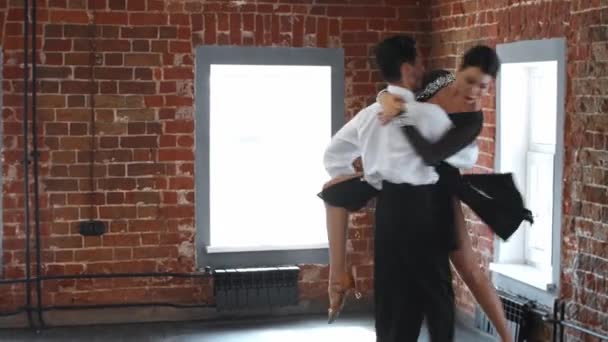 Una pareja en la realización de trajes de entrenamiento de su sensual número de baile en el estudio con paredes de ladrillo naranja — Vídeos de Stock