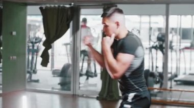 Kısa saçlı genç adam spor salonunda gölge boksu yapıyor.