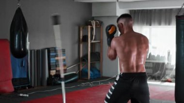 Üstsüz genç adam boksörlük eğitimini spor salonunda atlatmak için aldı.