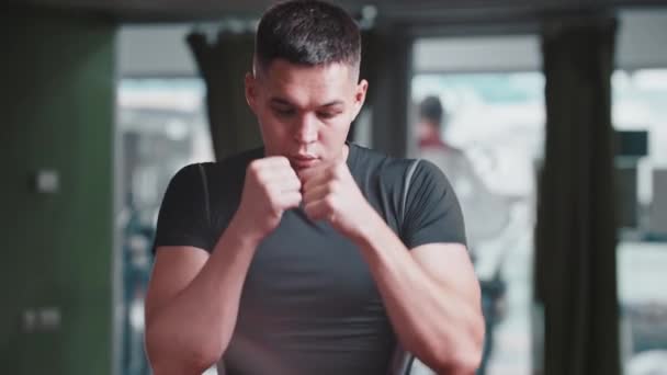 Fiatal férfi sportruhában árnyékbokszol az edzőteremben. — Stock videók