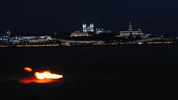 Маленький костер на пляже и городской пейзаж на заднем плане — стоковое видео