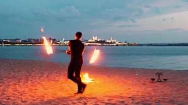Yangın gösterisi. Elinde meşale olan bir adam akşam vakti kumsalda dans ediyor.