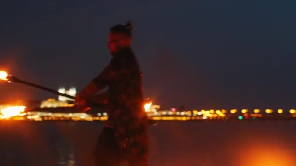 Espectáculo de fuego - un hombre en traje brillante bailando con dos antorchas de fuego en la playa nocturna — Vídeos de Stock