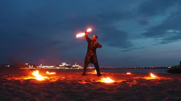 Feuershow - ein Mann tanzt nachts mit einer Fackel in der Hand am Strand — Stockvideo