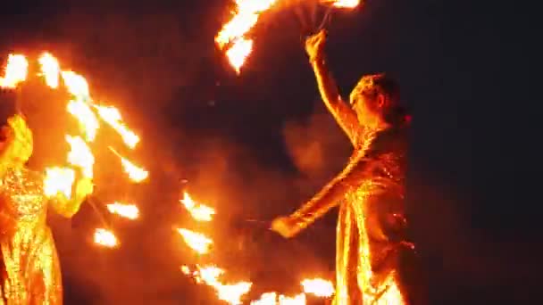 Огненное шоу - две женщины в блестящих платьях танцуют с зажженными факелами — стоковое видео