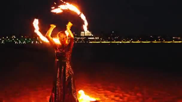 Fire show - two women in shiny dresses dancing with lit torches on the night beach — Stock Video