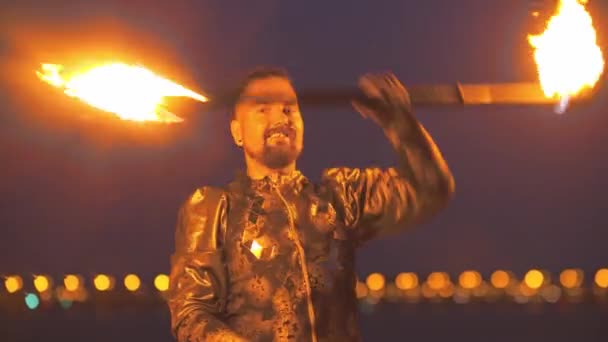 Улыбающийся человек с бородой играет с двухсторонним огненным факелом — стоковое видео
