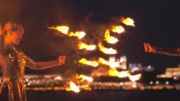 Две молодые женщины выступают с огненным шоу на пляже поздно вечером — стоковое видео