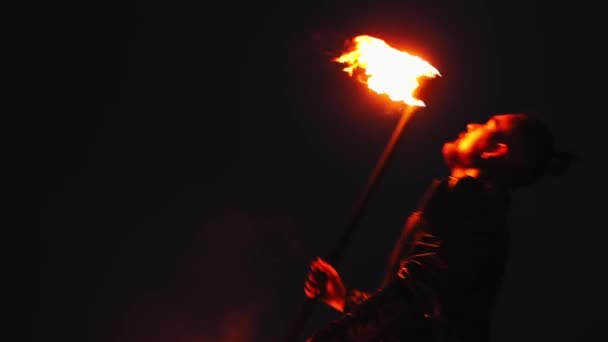 Бородач выплевывает бензин в огонь на ночном пляже. — стоковое видео