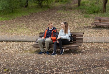 İki genç sonbahar boyunca parktaki bir bankta otururken sohbet ediyorlar.