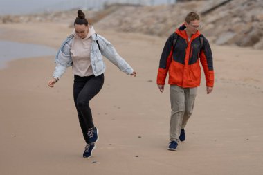 Genç yetişkinler sahilde rahat bir gezintinin tadını çıkarıyorlar. Açık havada eğleniyorlar.