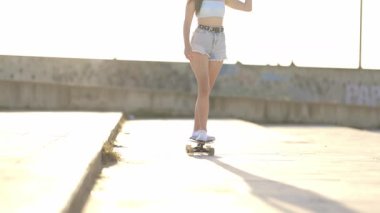 Güneşli bir günde beton bir şehir parkında sörf tahtası süren şık bir kadın.