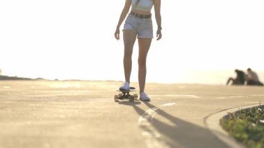 Güneşli bir günde kaldırımlı bir yolda uzun saçlı çekici bir genç kadın.