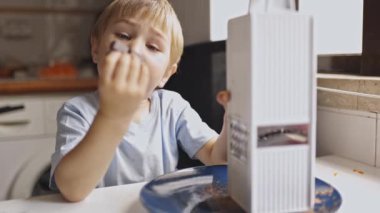 Mutfak masasında oturmuş, büyük bir zevkle çikolata yiyor.