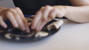 Yemek sırasında balık kemiklerini mavi bir tabakta bulunan etten ayıran kadın ellerini kapat.