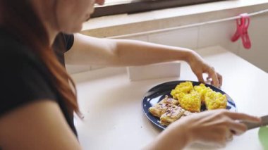 Kahvaltı için hamur işi yiyen ve çırpılmış yumurta yiyen genç bir kadın.