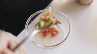 Gözlüklü kızıl saçlı kadın mutfaktaki cam kaseden sağlıklı sebze salatası yiyor.