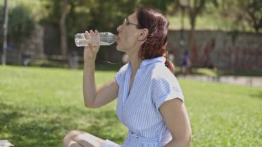 Parkta orta yaşlı bir kadın hasta, midesi bulanıyor ve su içtikten sonra kusmaya çalışıyor.