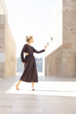 Güneşli bir günde uzun bir elbise içinde çıplak ayakla dans eden bir kadın.