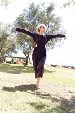 Genç kadın çimenlerin üzerinde çıplak ayakla dans ediyor, özgürlüğün ve hareketin tadını çıkarıyor.