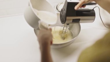 Pasta hamuru hazırlamak için elektrikli mikser kullanan bir kadın.
