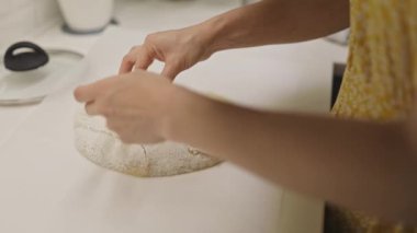 Bir kadının elleri kağıt üzerinde yoğurur, şekillendirir ve ekşi ekmek çizer.