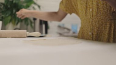 Kadınların elleri bir çatal batırmadan önce un kaplı bir yüzeyde hamuru hazırlar ve düzleştirir.