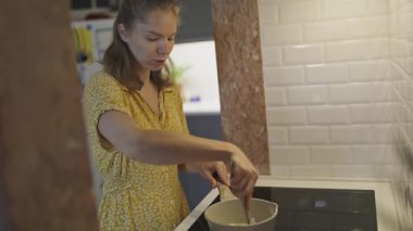 Çalışkan kadın indüksiyon sobasında sağlıklı ve lezzetli bir ev yemeği hazırlıyor.