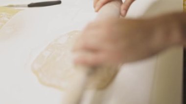 Dişi ellerin, un kaplı bir yüzeye ahşap bir okla yuvarlanan taze hamuru kapatmasını istiyorum.