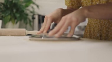 Mutfak tezgahında tencere kapağı kullanarak yuvarlak bir şekli hamura çeviren kadın ellerini kapatın.