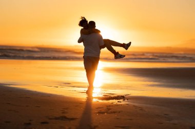 Çiftler, altın saat günbatımında sahilde romantik bir anın tadını çıkarıyorlar.