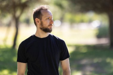 Man looking into the distance, reflecting in a park setting