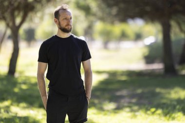 Bearded man enjoying fresh air and sunshine, looking into the distance with a thoughtful expression