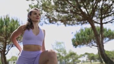 Young sportswoman performing leg stretches on a yoga mat in a sunny park before her workout