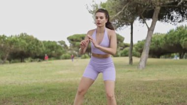 Fit young woman in sportswear doing a leg workout routine with squats and lunges in a city park