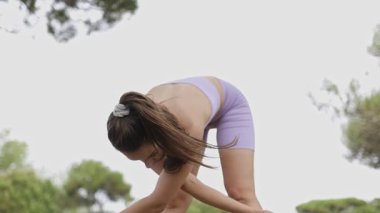 Fit young woman performing warm up exercises and stretches outdoors before a workout session
